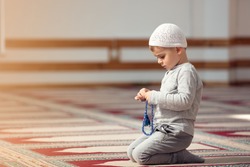 The Muslim child prays in the mosque, the little boy prays to God, Peace and love in the holy month of Ramadan.