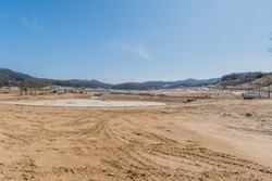 Landscape of construction site under clear blue sky with mountains in background.