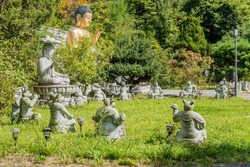 Statues of animals of Chinese horoscope and seated stone and bronze Buddha in garden of Buddhist temple.