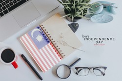 Notebook with Malaysia Flag on white office table with text Happy Independence day 31st August.