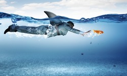 Young businessman with shark flipper swiming under water