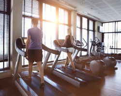 Healthy man and woman running on a treadmill in a gym. Sport and health concept