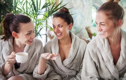 Three young happy women drinking tea at spa resort