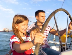 Young father with adorable daughters resting on a big boat