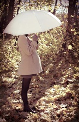Young pregnant woman under umbrella in autumn forest