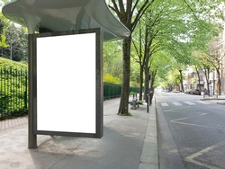 Blank bus stop billboard Mockup in empty street in Paris. Parisian style hoarding advertisement close to a park in beautiful city