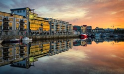 morning view on row of buildings and fishing boats in Galway Dock with sky reflected in the water, HDR image