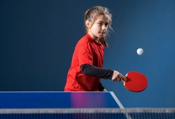 Little charming happy girl child plays ping pong on indoor