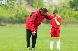 Kids soccer football - coach comfort little soccer player who is crying after a missed goal