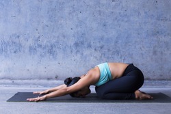 Young woman practicing yoga, childs pose, resting.