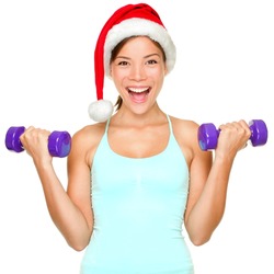 Fitness christmas woman training lifting hand weight wearing santa hat. Female model working out smiling happy and excited isolated on white background.