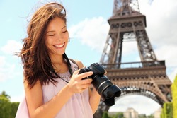Paris Eiffel Tower tourist with camera taking pictures in front of the Eiffel tower, Paris, France. Young photographer woman in her 20s.