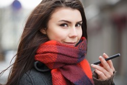 Portrait of beautiful white girl smoking vape pen.Pretty young woman smokes electronic cigarette device.Happy smoker female hold ecig gadget with glycerin eliquid.Bad habit background