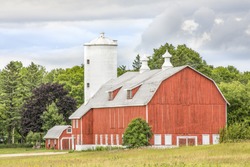 A large red barn with a tall white silo stands in scenic Door County, Wisconsin.