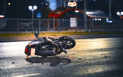 Motorcycle lying on asphalt after an road accident. Moto bike collision at night. Damaged motorcycle lay on asphalt road