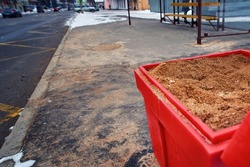 Grit bin, sand box with sand for improve traction on snowy and icy sidewalk at bus stop, road maintenance in winter season. Plastic grit container, spread sand to prevent slipping. SELECTIVE FOCUS