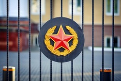 Red star on the gate of General Staff of the Armed Forces of Belarus. Heraldic sign, emblem of the Armed Forces. Five-pointed red star with and golden edging, wreath of golden oak and laurel branches