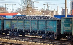 Coal freight train loaded with coal. Train transports fossil fuel. Train cars full of coal at railway station. Coal embargo, ban and restrictions concept