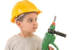 Little kid as a construction worker wearing yellow helmet holding drill like a gun.White background studio picture.