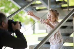 Father taking picture of smiling young girl outdoors