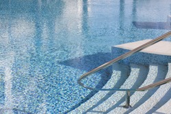 Rails and stairs leading into a blue swimmingpool