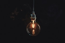 Vintage edison lightbulb on dark background with bright yellow shining wire