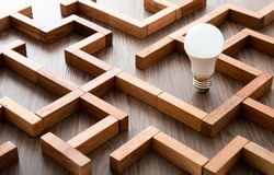 Light bulb in the maze game built by wood blocks, finding the right way to the success, searching creative idea concept