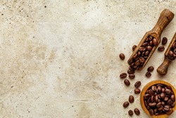 Coffee composition with copy space concrete background. Rough light stone wall texture with empty space and wooden spoon, bowl with fresh roasted beans and several scattered seeds