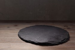 Slate pizza cutting board for homemade bread cooking or baking on table. Empty pizza board at wooden tabletop background. Bakery concept in kitchen