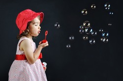 Little girl playing with soap bubbles