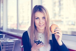 Caucasian attractive woman working using mobile smart phone and laptop eating burger in restaurant background. Text messaging, online banking, playing game, watching video or e commerce shopping