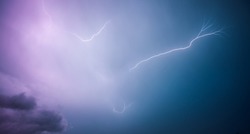 A strong storm with bright lightning illuminating ominous clouds. Exotic image of the texture of storm clouds. Adverse weather conditions. Picturesque photo wallpaper. Climate change. Force of nature.