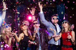 Cheerful young people showered with confetti on a club party.