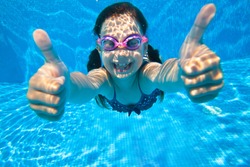 little girl dives into the water and shows the gesture OK