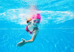 little girl in a striped bathing suit swims in the pool underwater