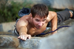 Photo of young man climbing up the rock