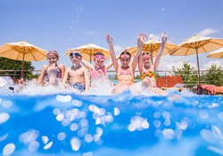 Children play fun with splashes on the side of the pool at the resort