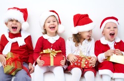 Group of four children in Christmas hat with presents