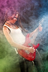 Fashion african american girl with guitar playing hard-rock. Colored fog and light on black background