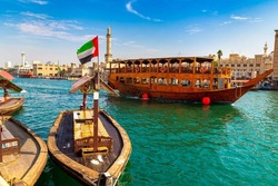 Dhow - old traditional wooden ship and Grand Bur Dubai Masjid Mosque  on the bay Creek in Dubai, United Arab Emirates
