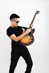 Young asian guy guitarist standing arched back playing solo over isolated white background with a sunburst brown semi hollow body