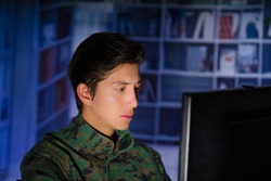 Portrait of handsome young soldier wearing a military uniform, military drone operator watching at his computer