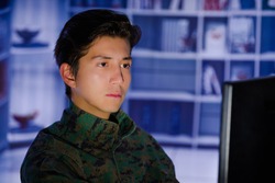 Portrait of handsome young soldier wearing a military uniform, military drone operator watching at his computer