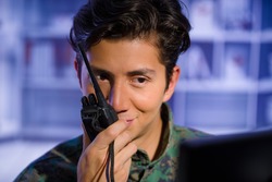 Portrait of young soldier wearing a military uniform, military drone operator watching at his computer and using a radio to give an advice