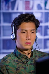 Portrait of sad soldier wearing a military uniform, operating at his computer and talking through his headphones to give an advice, in a blurred background