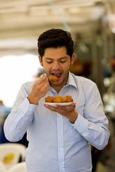 Close up of a handsome young man eating a homemade fritters with sugar and its ingredients
