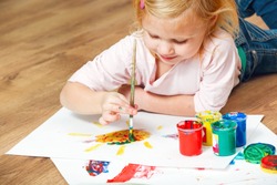 Cute little redhead girl painting with brush.