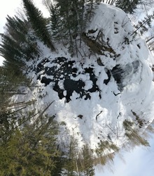 little planet small planet  panoramic aerial view waterfall on small mountain river in winter forest with snow-covered trees