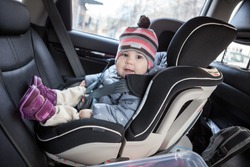 Child safety seat with smiling infant child is on back seat of car, a kid eight month old