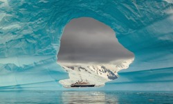 Steamer ship seen through the hole in the iceberg at Antarctic peninsula
